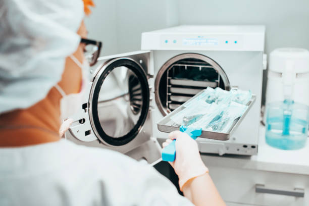 autoclave - esterilización de instrumentos médicos - una enfermera carga una bandeja en un autoclave - artículo médico fotografías e imágenes de stock