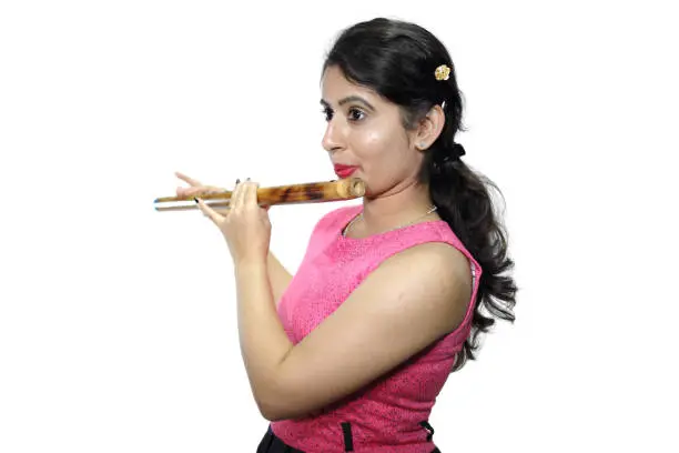 Young woman in casual wear playing bansuri, a kind of traditional Indian musical instrument.