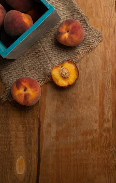 Fresh ripe peaches fruits in blue box on wooden rustic background. Top view.