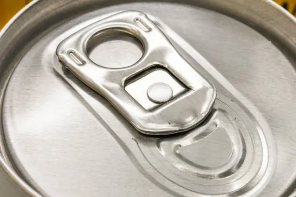 Close up view of the ring pull on an unopened can of drink. The cans are made of aluminium. No people.