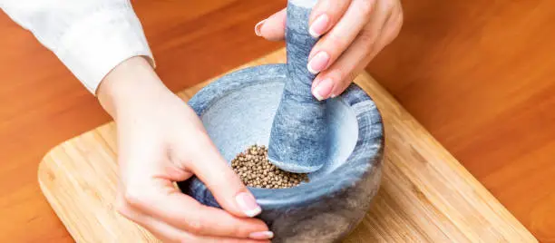 Photo of Hands of woman grinding pepper in mortar