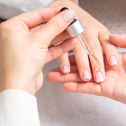 Manicurist vierte aceite en las uñas de la mujer photo