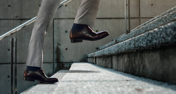 istock Motivation and challenging Concept. Steps Forward into a Success. Low Section of Businessman Walking Up on Staircase 1249357587