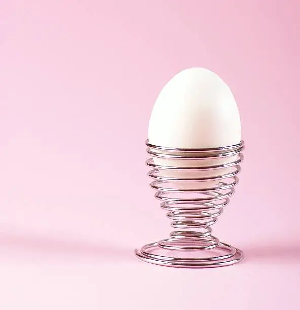 Eggcup and white egg on pink background.