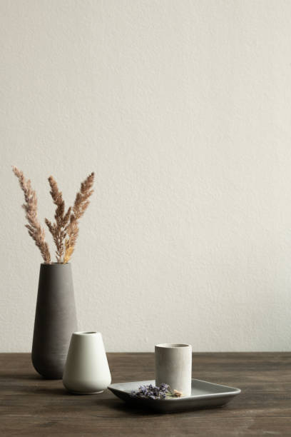 istock Two white ceramic vases standing on wooden table on background of black one 1249361077