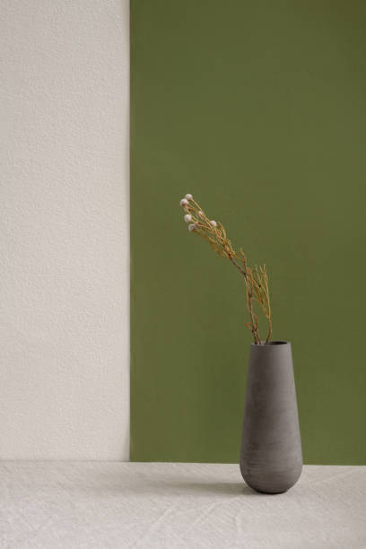 istock Grey ceramic or clay handmade vase with dried wildflowers standing on table 1249361165
