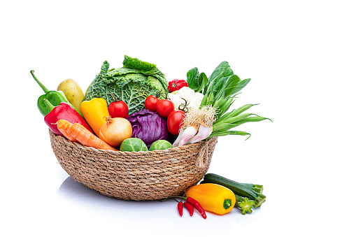 Healthy food: fresh multicolored organic vegetables for preparing a healthy meal arranged in a basket  shot on white background. Vegetables included in the composition are tomatoes, onion, carrot, green beans, bell pepper, chili pepper, herbs, cabbage, potatoes, among others. High resolution 42Mp studio digital capture taken with Sony A7rII and Sony FE 90mm f2.8 macro G OSS lens