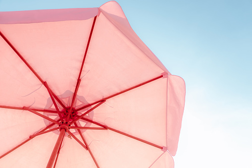 Pink umbrella against the sky on a chill vacation. Summer Holiday and Travel Concept