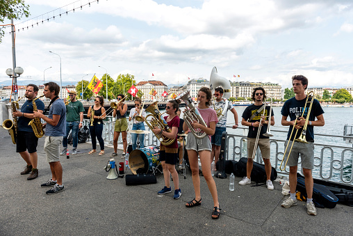 Geneva, Switzerland - August 24, 2018: The bare brass band busking at Geneva, Switzerland. Young boys and girls are earning money by using classic musical instruments (trombone, saxophone, oboe, drums) in street of Geneva. They are street musicians.