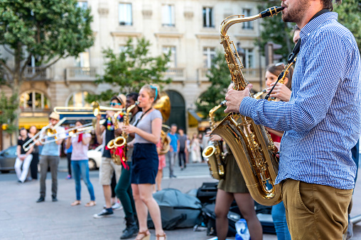 Paris, France - July 7, 2016: The bare brass band busking at Paris, France (Saint-Michel District). Young boys and girls are earning money by using classic musical instruments (trombone, saxophone, oboe, drums) in street of Paris. They are street musicians.