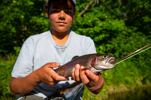 A young fly-fisherman with a rainbow trout