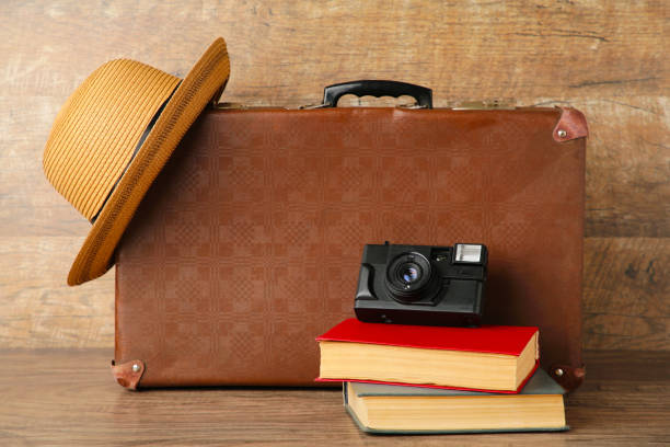 istock Old suitcase and books with camera on brown background 1249365361