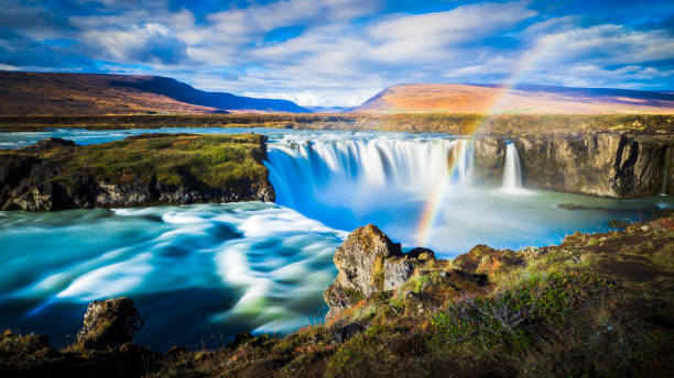 istock dynamic longtime exposure wide angle panorama of magical godafoss waterfall with romantic rainbow and hills in the background nearby fossholl in iceland 1249366815