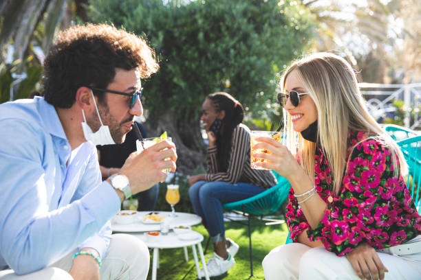 istock Happy group of multi ethnic friends enjoying some refreshing drinks wearing protective face mask 1249368608