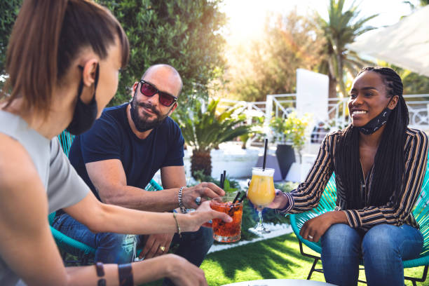 istock Happy group of multi ethnic friends enjoying some refreshing drinks wearing protective face mask 1249368724