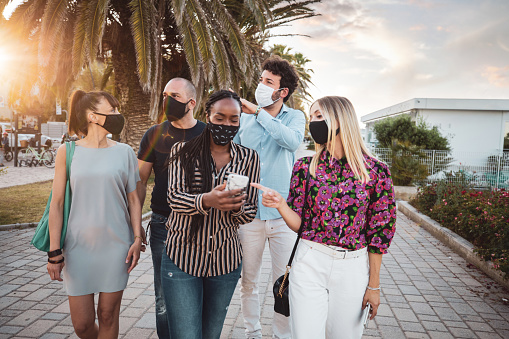 Multi ethnic group of friends meeting in the city wearing protective face masks having fun together after the lockdown which last for a couple of months.