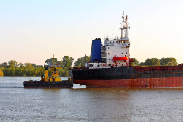 istock Small tugboat pushes a big broken ship along the Danube River 1249369966