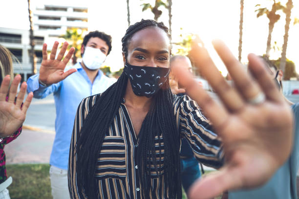 istock Friends wearing protective mask waving to the camera 1249369993