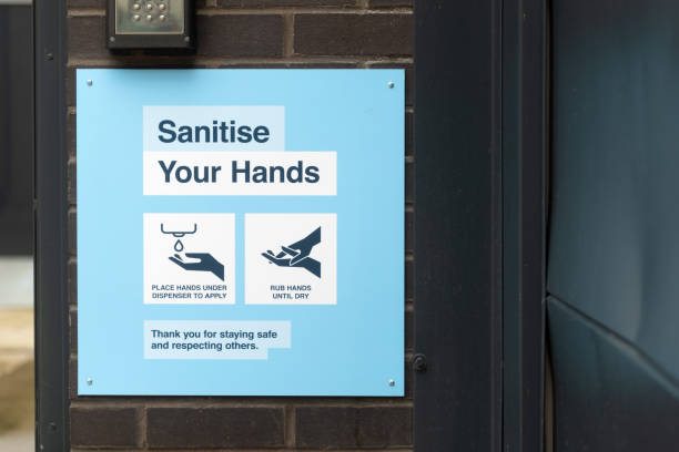 A sign displaying COVID-19 Sanitise Your Hands safety information outside office building downtown.