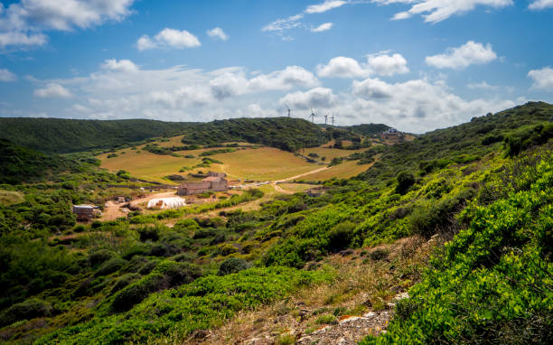 istock old farmhouse in the sunlight in a overgrown valley between hills under nice cloudscape with windmills at the horizon nearby es grau, minorca 1249373276