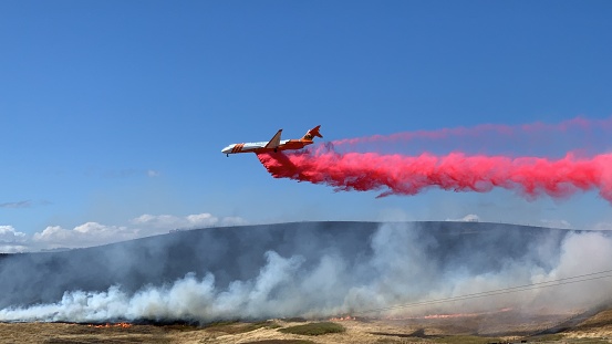 747 plane making a drop of fire retardant over a vegetation fire in the Sonoma Hills