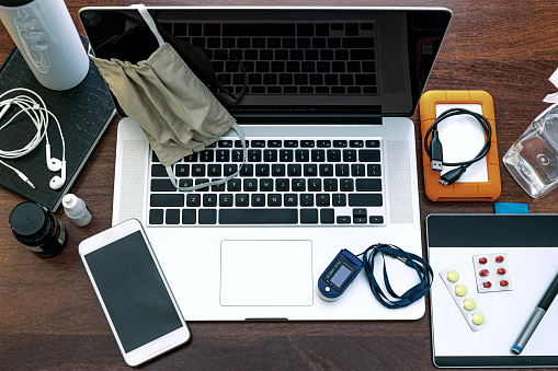 View of the black screen of the laptop and equipment to work at home, do research, agenda, HD, mobile phone, headset, surgical mask, pff2 mask and pulse oximeter.