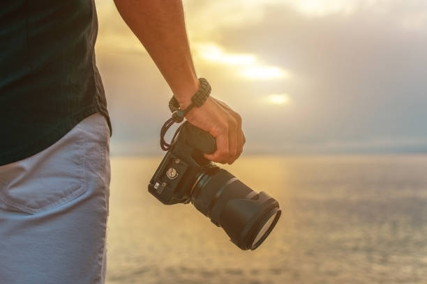 istock Man holds a camera in his hand at sunset. 1249378335
