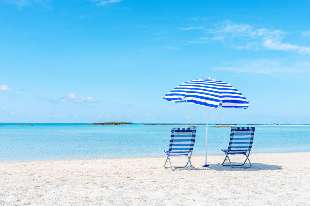 istock Two chairs under umbrella on tropical beach. Summer vacation concept. 1249384067