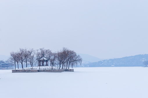 The snow covered park is full of white. The lake is frozen, and the Chinese Pavilion surrounded by trees in the center of the lake is very beautiful.