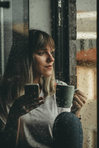 Raindrops, Woman Looking Out The Window and Drinking Coffee