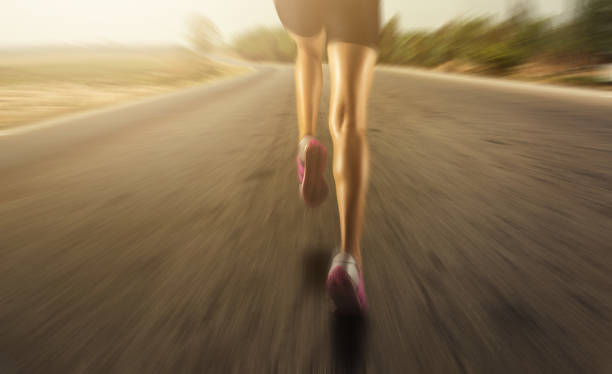 fondo deportivo. los pies del corredor corren en el primer plano de la carretera en el efecto shoe.zoom - running jogging women marathon fotografías e imágenes de stock