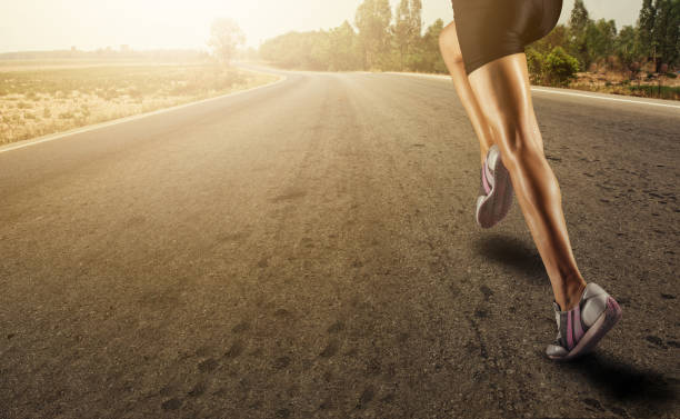sports background. runner feet running on road closeup on shoe.flare light - running jogging women marathon imagens e fotografias de stock