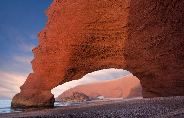 Famous Red arch at Legzira Beach on Atlantic coast in Morocco, North Africa Famous Red arches at Legzira beach near Sidi Ifni on Atlantic coast in Morocco, Northern Africa. One of two rock archways has collapsed in 2016. sunset agadir marocco stock pictures, royalty-free photos & images