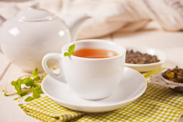 tasse de thé vert ou noir frais avec de la menthe sur la table en bois blanc. boisson détox et antioxydante. - tea chinese tea heat teapot photos et images de collection