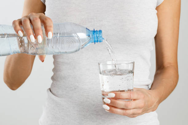 istock Athletic woman pours water from a bottle into a glass. 1249397732