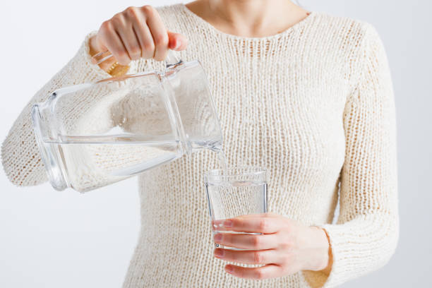 istock A woman pours water from a decanter into a glass. 1249398370