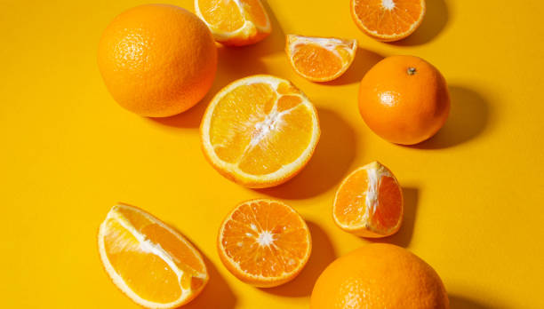 istock Oranges and tangerines whole and cut into pieces on a bright yellow background. Minimalistic background. 1249398778