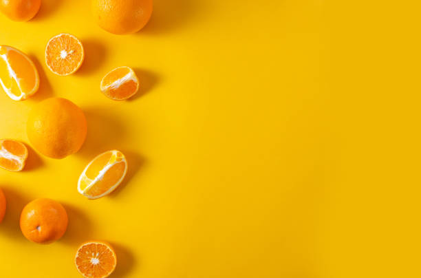 istock Oranges and tangerines whole and cut into pieces on a bright yellow background. Top view, flat lay, copy space, minimalist concept 1249398779