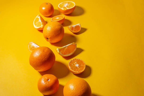 istock Oranges and tangerines whole and cut into pieces on a bright yellow background. minimalist concept, copy space 1249398780