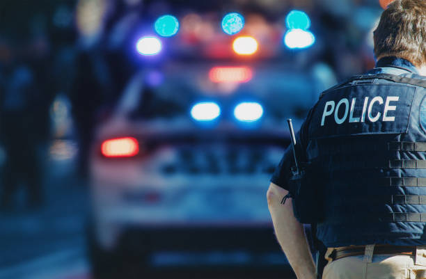 American policeman and police car in the background NEW YORK, USA - 01 MAY, 2020: Police officers performing his duties on the streets of Manhattan. officer military rank stock pictures, royalty-free photos & images