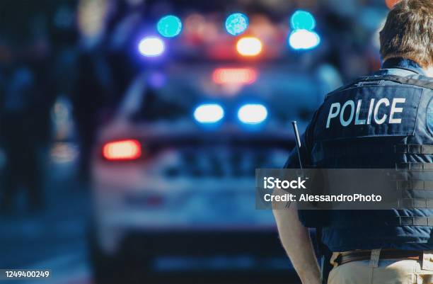 American Policeman And Police Car In The Background Stock Photo - Download Image Now