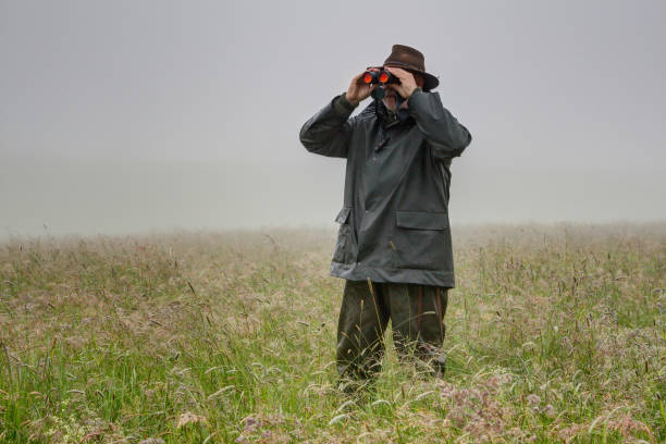 istock Hunter stands with rainwear in the high meadow. 1249400568