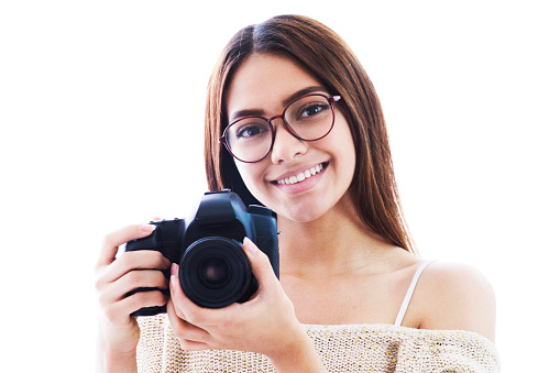 Young woman holding her camera close to her face smiling - Studio shot