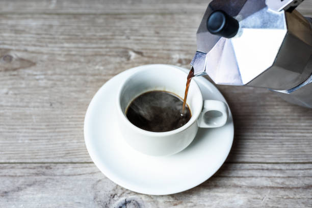 istock filling a white cup with hot coffee from an italian mocha pot. Selective focus. 1249402071