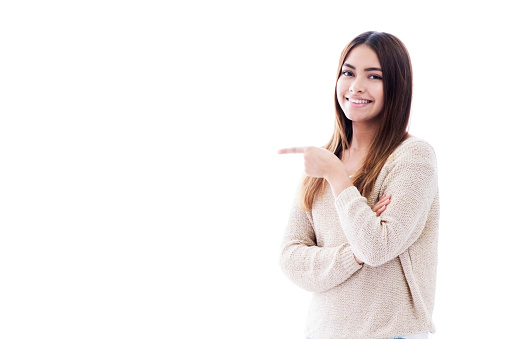 Beautiful woman pointing at side facing camera smiling - Copy space - Studio shot