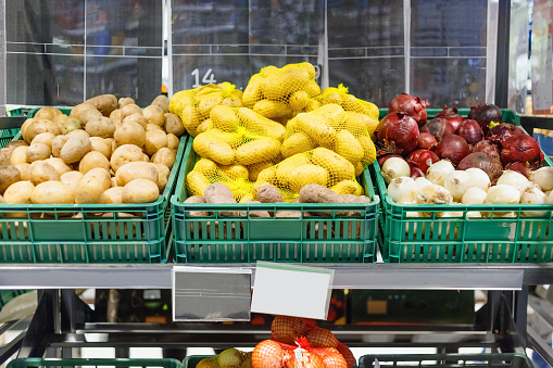 Boxes with ripe fresh potatoes and onions on shelves