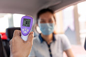 taxi driver using infrared thermometer to check passenger body temperature
