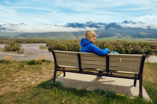 Senior woman relaxing on a bench at a popular viewpoint above the Yellowstone River at Paradise Valley, Montana, USA.