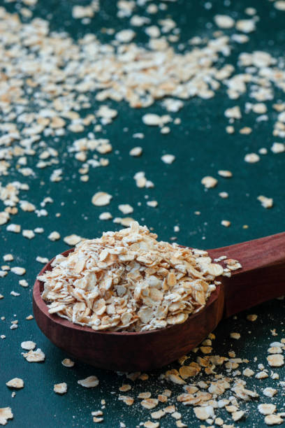 heap of rolled oats with wooden spoon - oat imagens e fotografias de stock