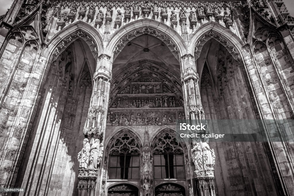 Ulm Minster or Cathedral of Ulm city, Germany. It is top landmark of Ulm. Front view of ornate entrance of old Gothic cathedral, Ulm Minster or Cathedral of Ulm city, Germany. It is top landmark of Ulm. Front view of ornate entrance of old Gothic cathedral, luxury facade of famous medieval Christian church in black and white. Germany Stock Photo